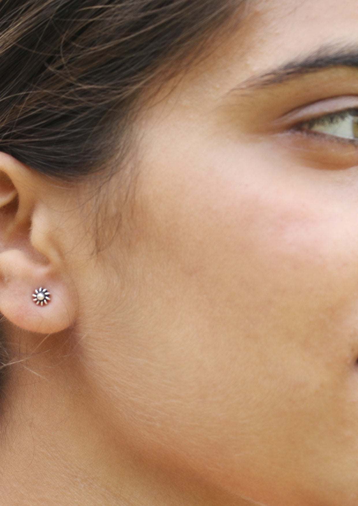 Close-up of a woman wearing a sterling silver wire spring petal flower stud with secure butterfly backs