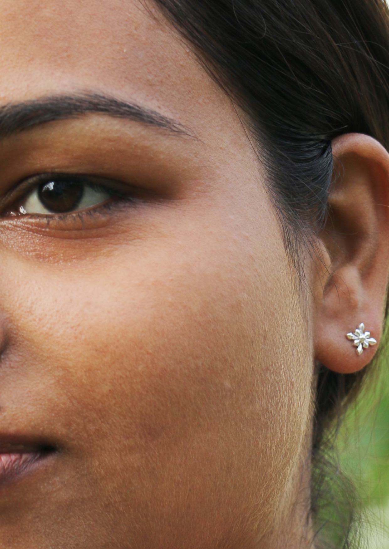 Close up of a person wearing a silver starflower studs with secure butterfly backs