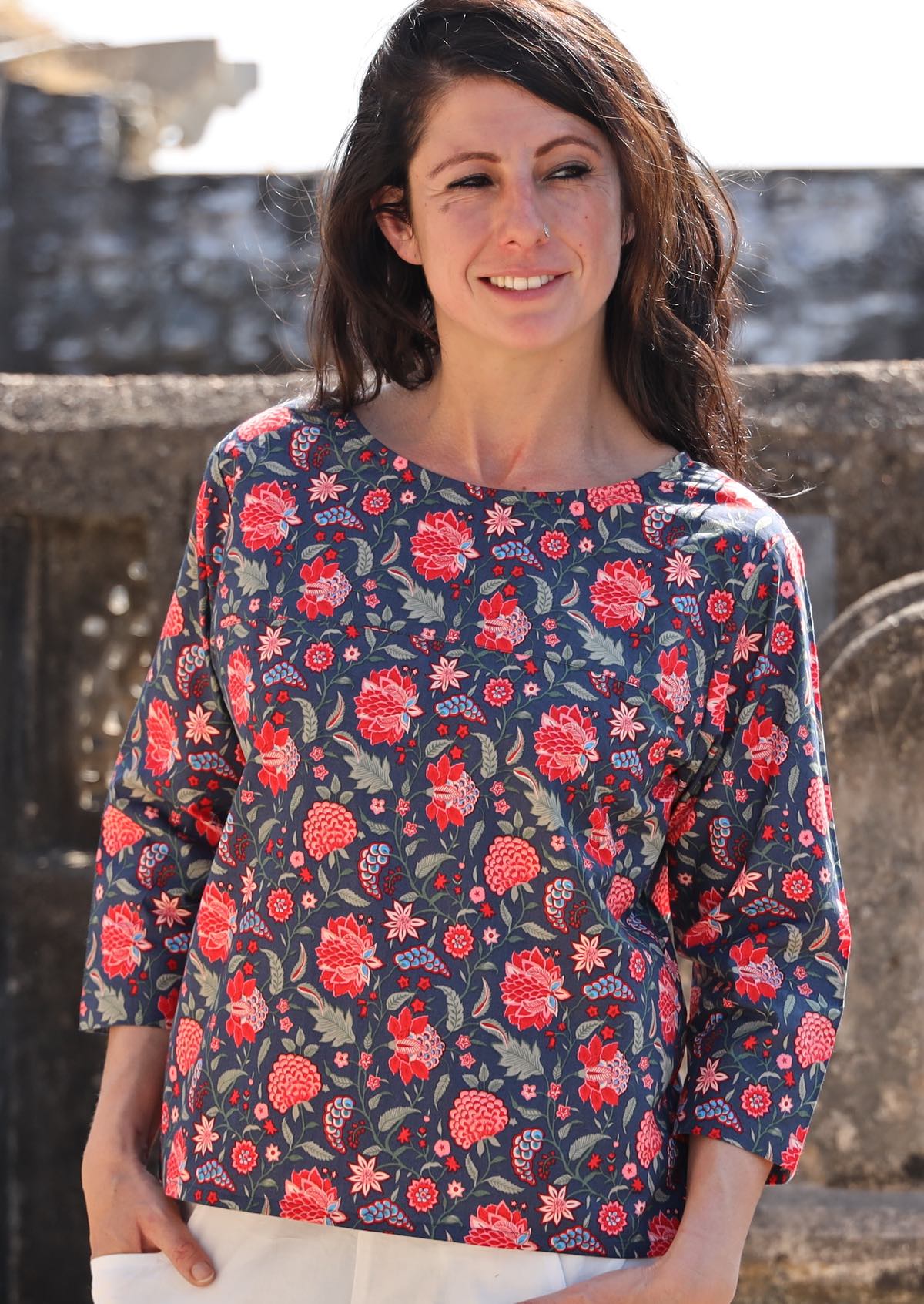 Woman wears 3/4 sleeve cotton boxy top in floral print on a blue base