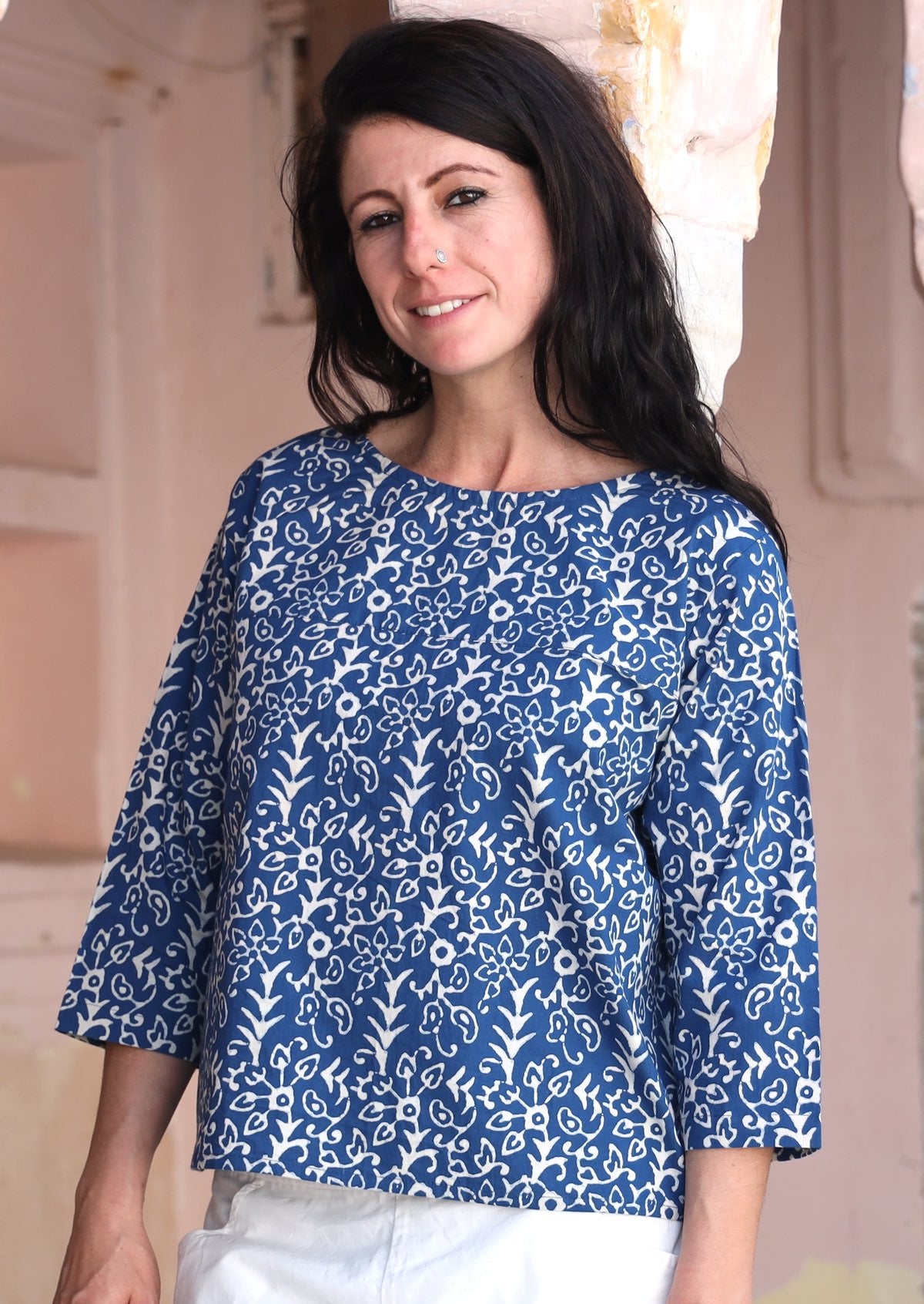 Woman wears relaxed fit cotton top with 3/4 sleeves and round neckline in navy blue and off white floral print