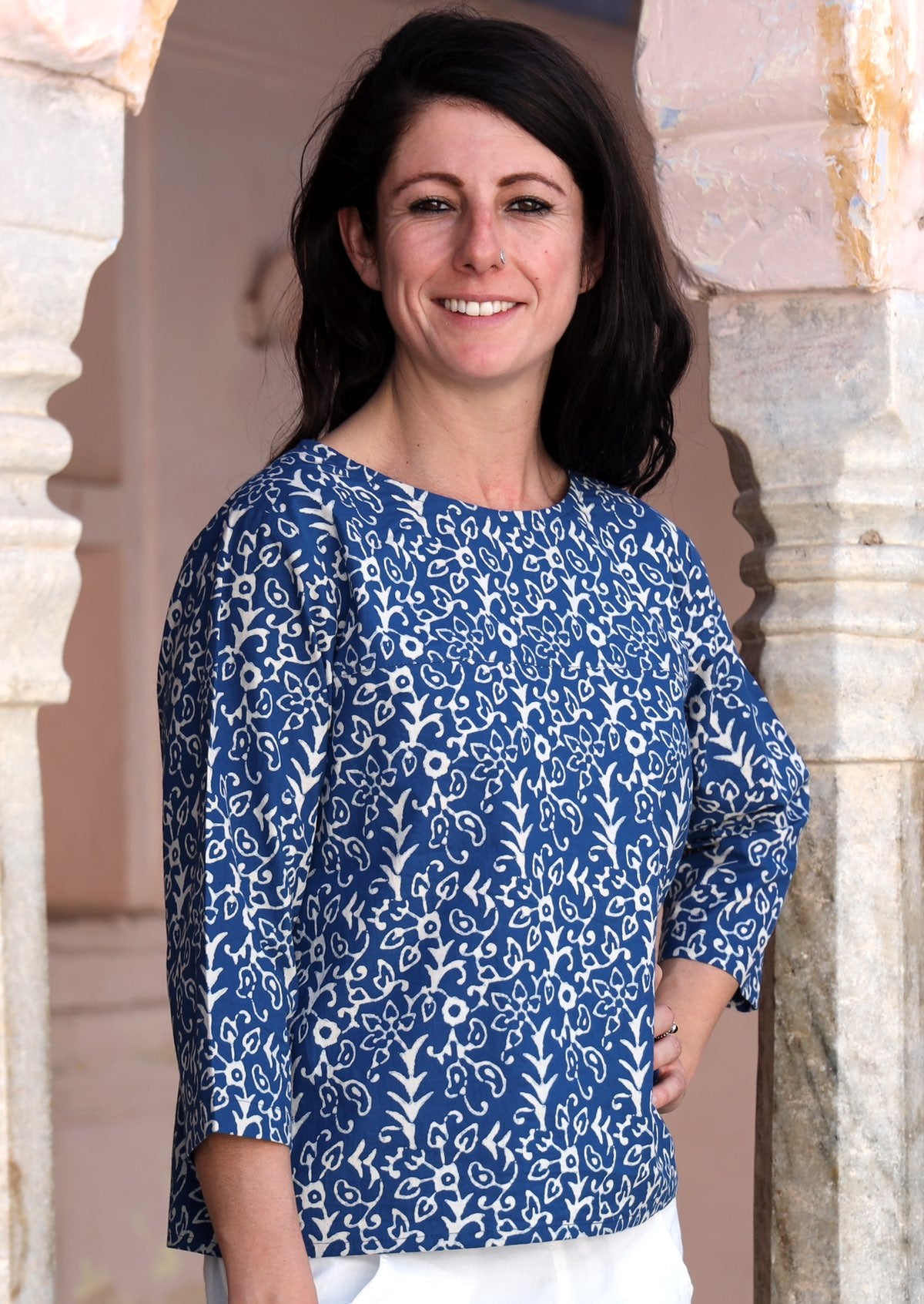 Woman stands sideways with hand on hip in cotton loose fit top with 3/4 sleeves and round neckline