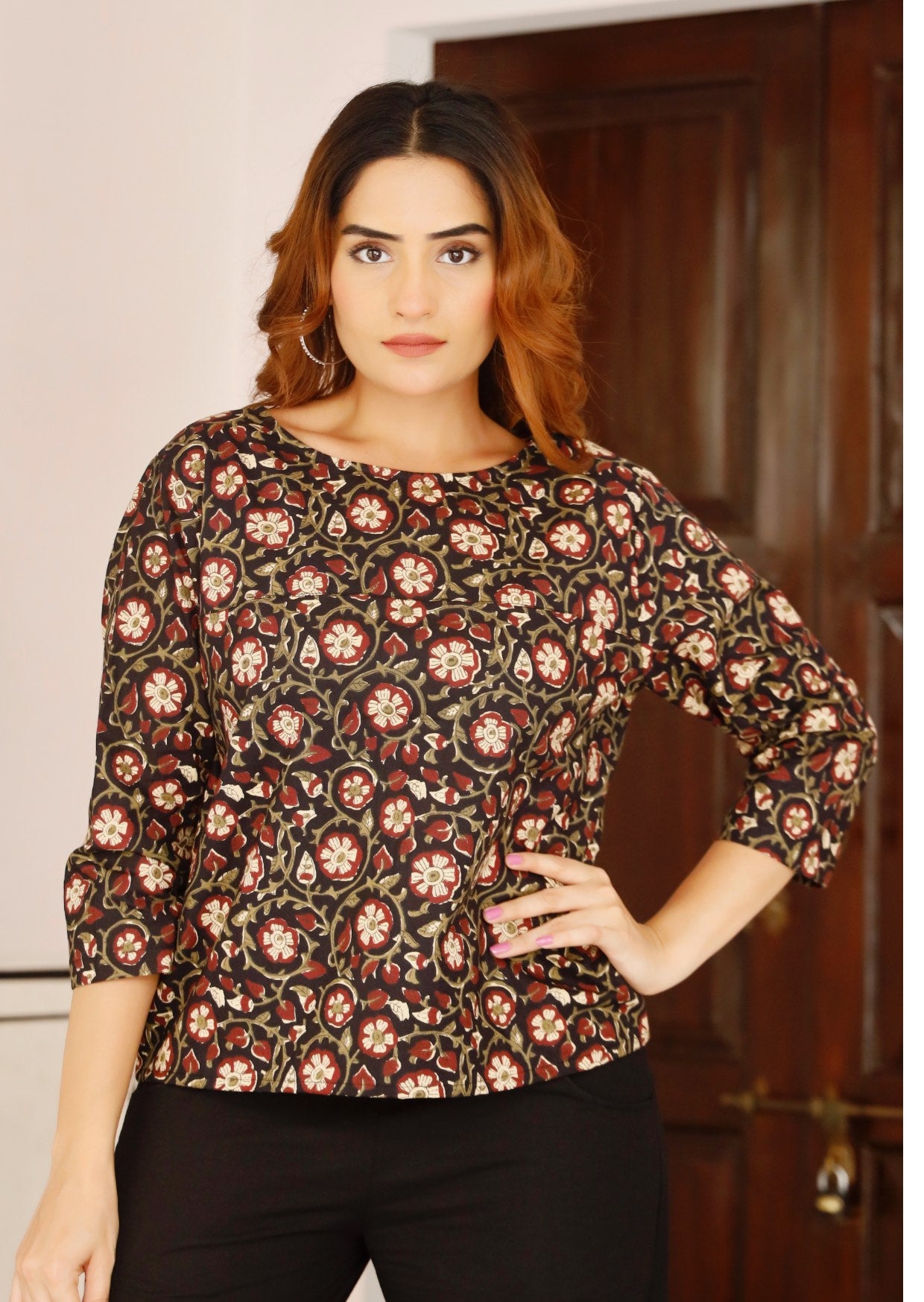Model wears relaxed fit black cotton top with 3/4 sleeves and round neckline in maroon, cream and olive floral print