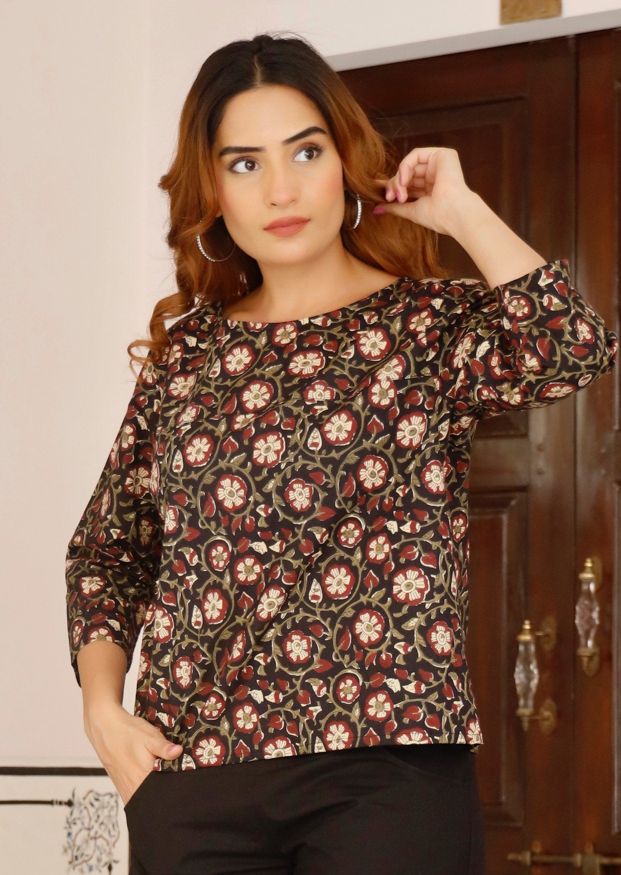 Model poses in relaxed fit top with 3/4sleeves in beautiful black based indian floral print.