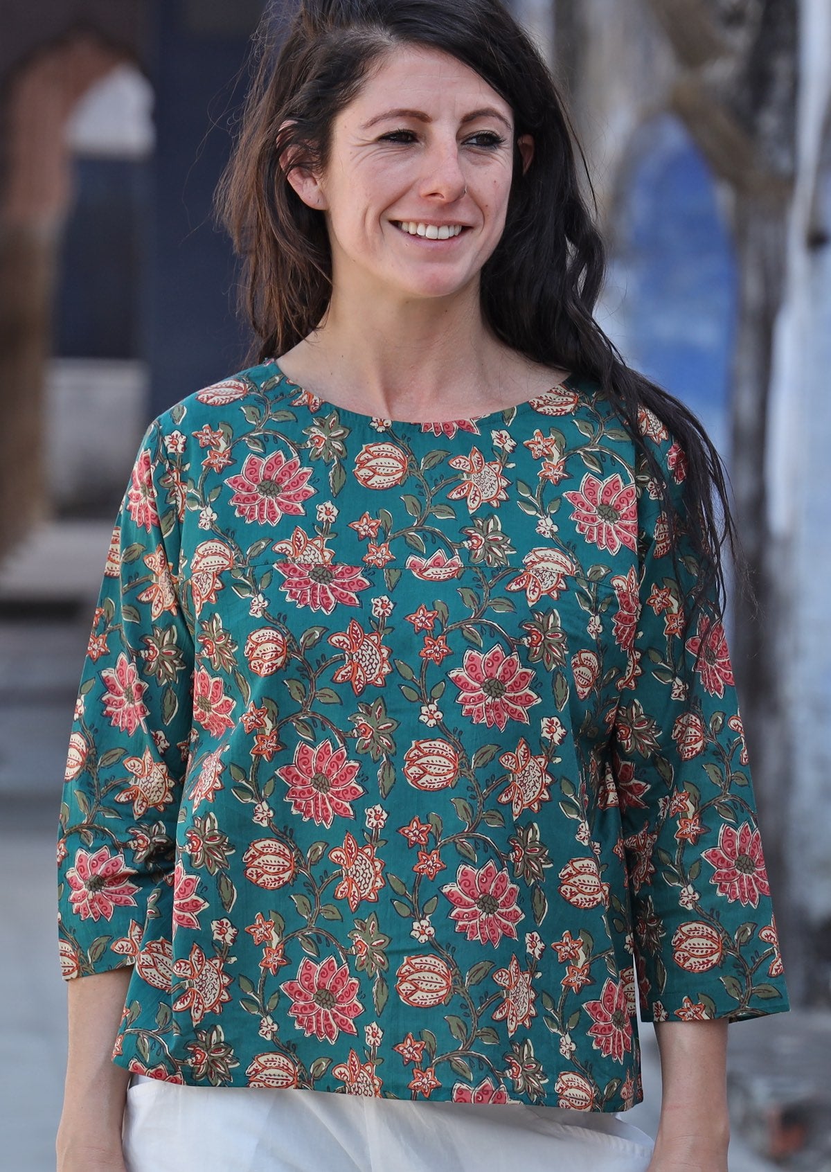 Woman smiling wearing relaxed fit cotton top with 3/4 sleeves and round neckline in green with a floral print