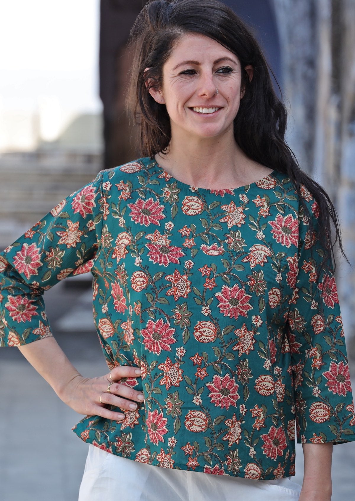 Model with hand on hip wears relaxed fit cotton top with 3/4 sleeves and round neckline in green  and floral print