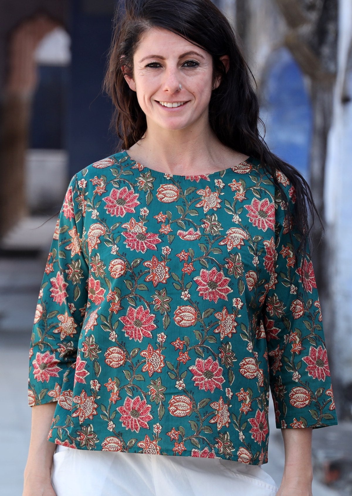 Model wearing relaxed fit cotton top with 3/4 sleeves and round neckline in green and floral print