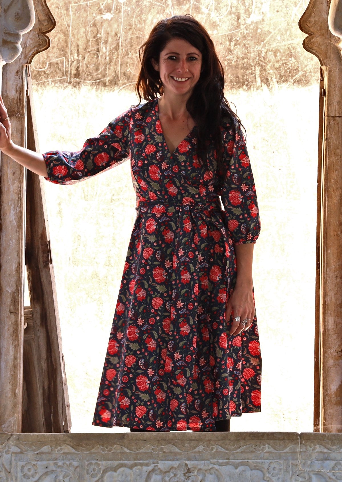 Model wearing 3/4 sleeved navy blue based cotton wrap dress with V-neckline and pockets.