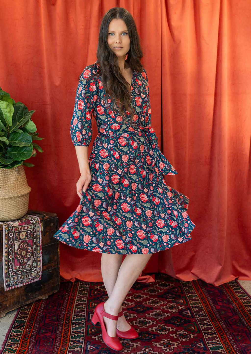 Model twirls in floral print cotton wrap dress holding the skirt out