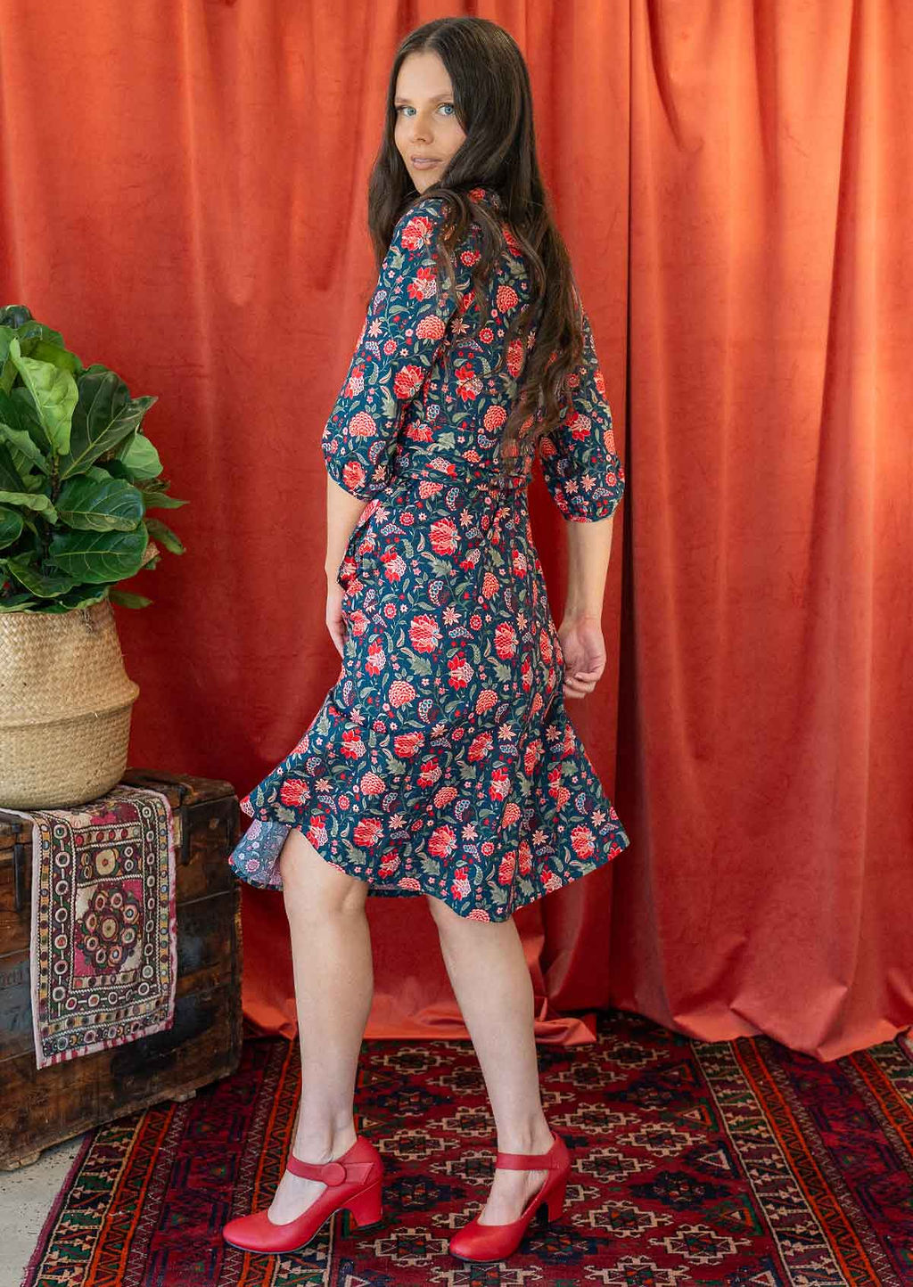 Woman twirls in floral print cotton wrap over the knee length dress, swishing the skirt