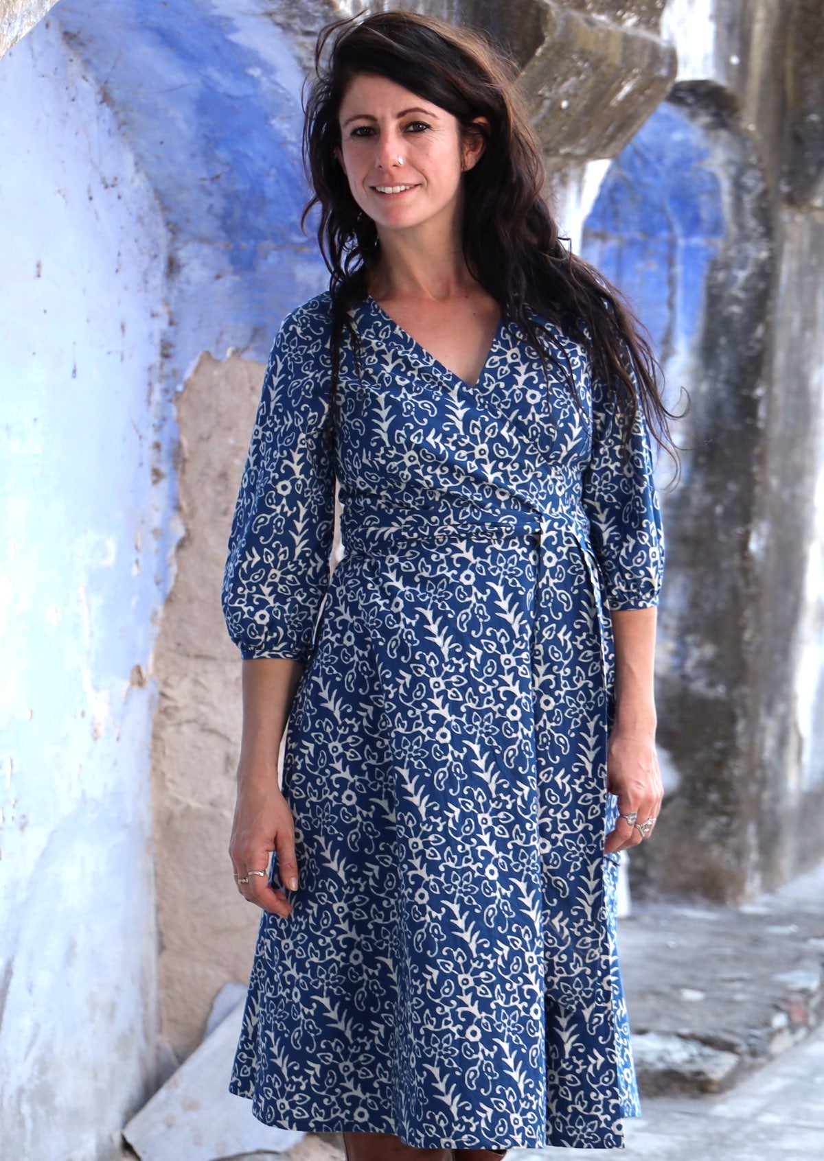 Front pose of model wearing cotton wrap dress with 3/4 sleeves in a white floral print on a blue base