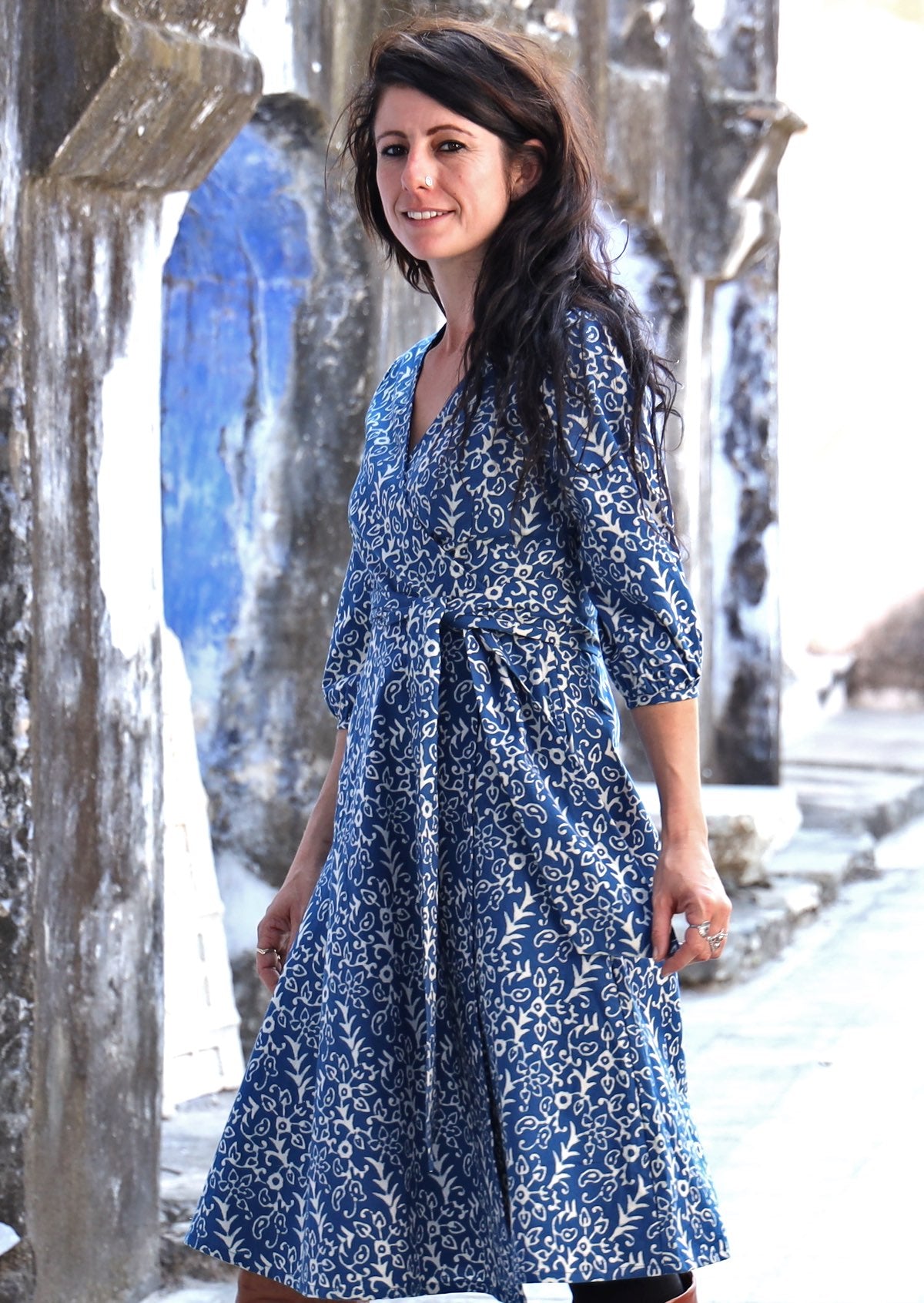 Model wearing 3/4 sleeved blue based cotton wrap dress with V-neckline
