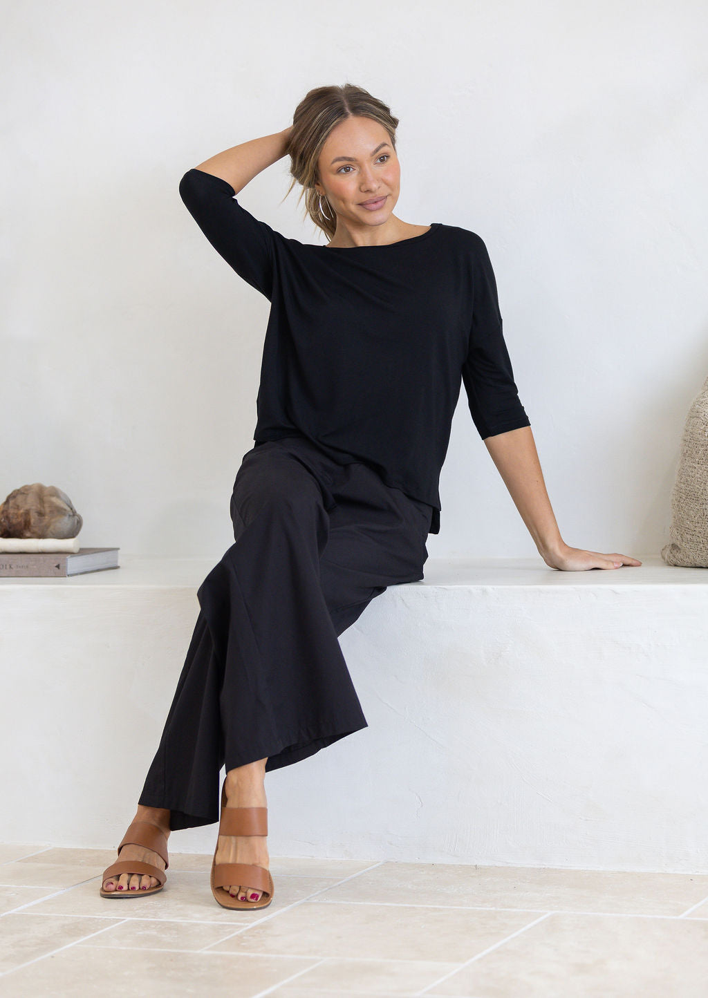 Woman wearing a black stretch rayon top paired with black cotton pants sitting on a bench