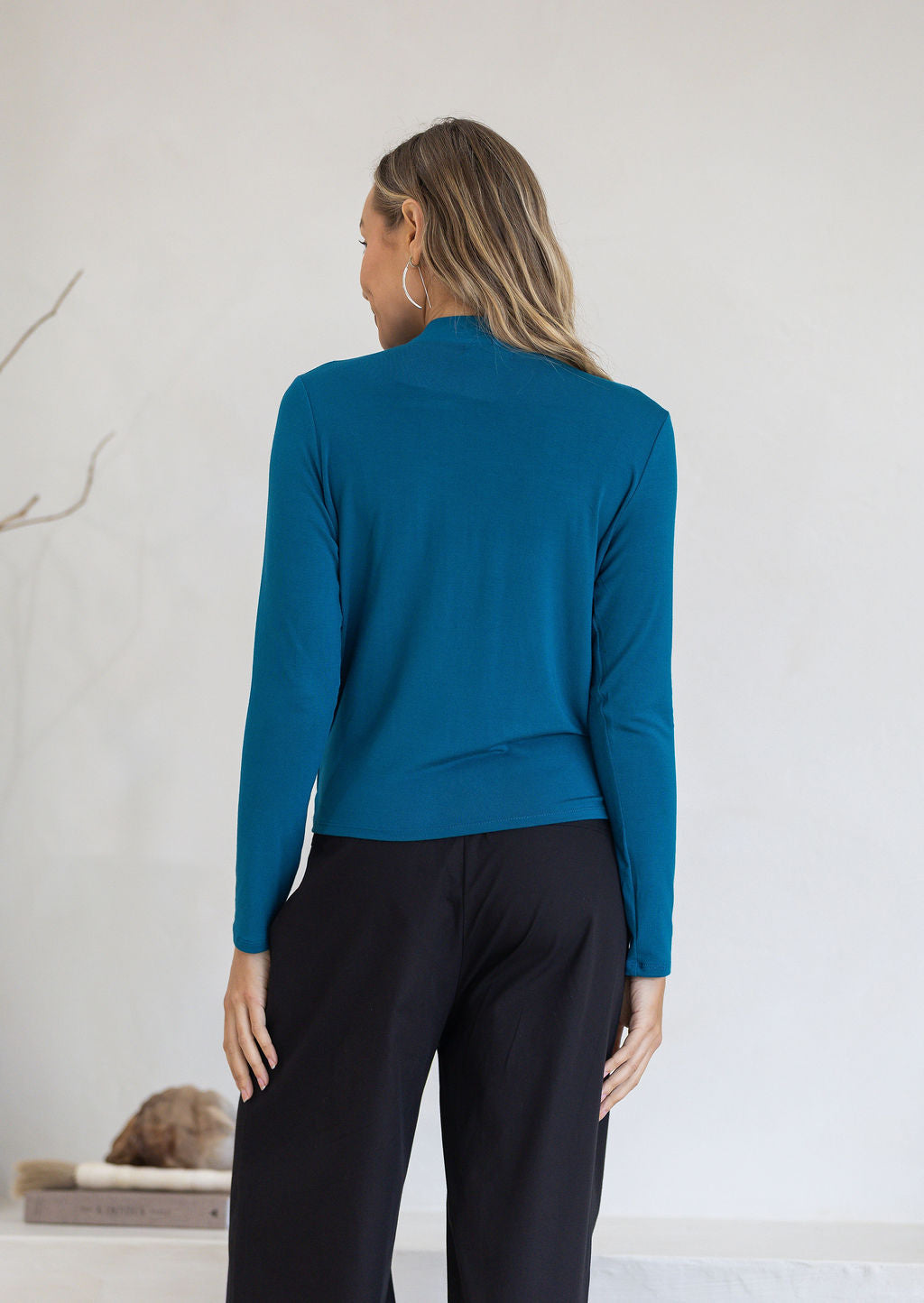Back view of woman in teal stretch rayon false wrap top with long sleeves