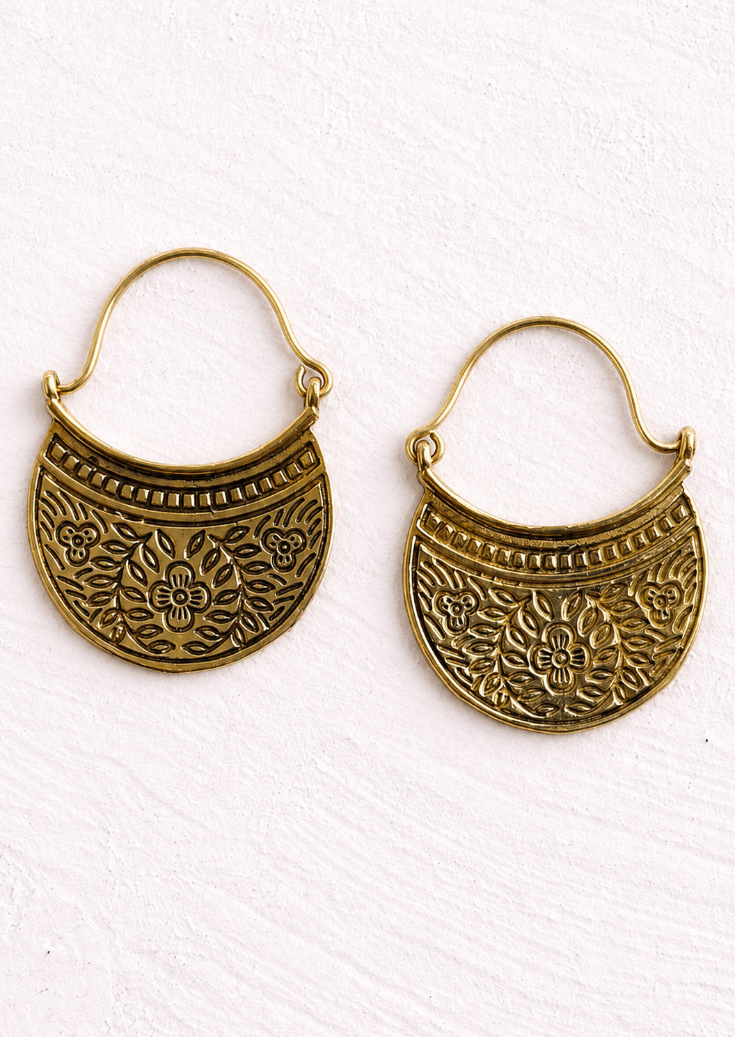Pair of gold coloured, curved crescent earrings with beautiful floral detailing. The embossed flower and leaf design gives them a lovely handcrafted feel and an earthy, antique-style finish.