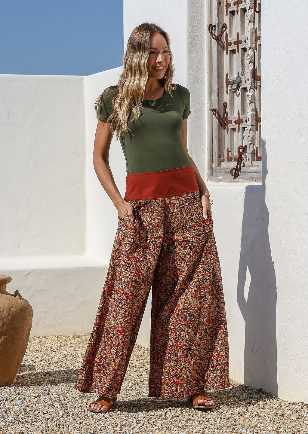Woman wearing a green top and wide legged patterned cotton pants standing with her hands in her pockets