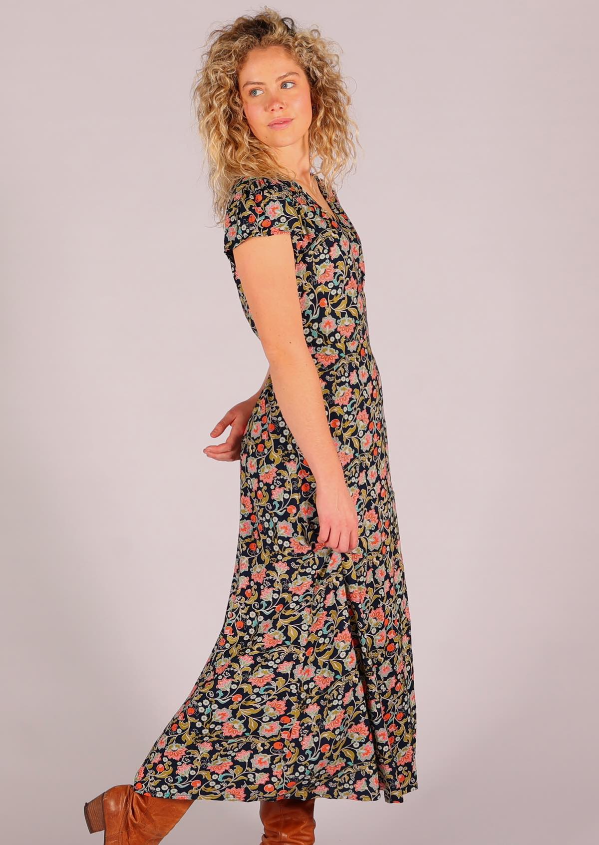 Model standing side on with one hand behind back wearing navy floral rayon wrap maxi sundress