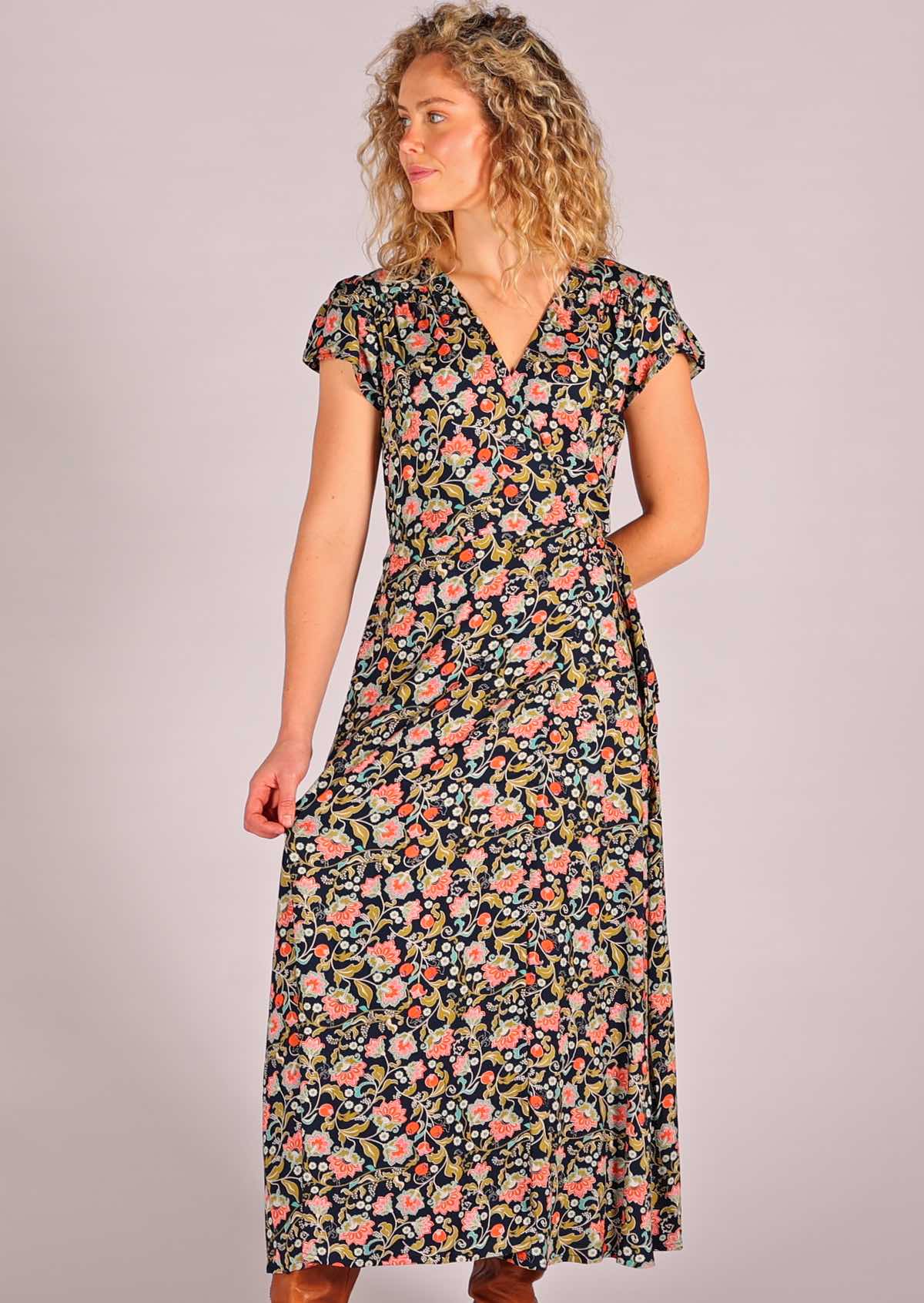Model standing holding one side of skirting of navy floral rayon wrap maxi sundress
