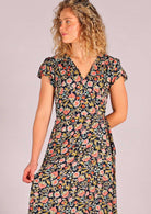 close up of model standing holding one side of skirting of navy floral rayon wrap maxi sundress