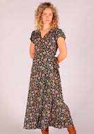 Model standing with hands behind back wearing navy floral rayon wrap maxi sundress