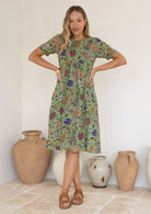 Woman wearing a green based floral print, 100% cotton dress.