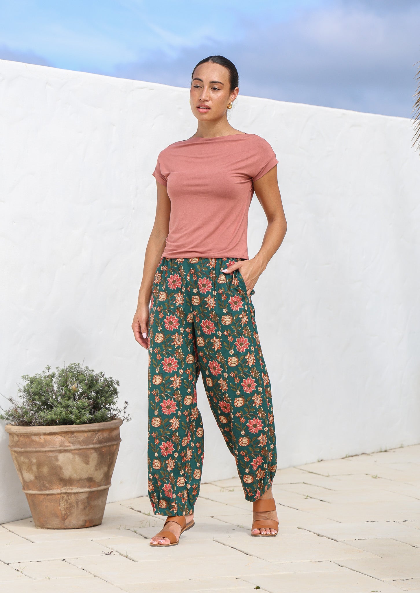 Model wearing 100% cotton tapered pants with pleats at ankles, pockets and elastic either side of the waist.