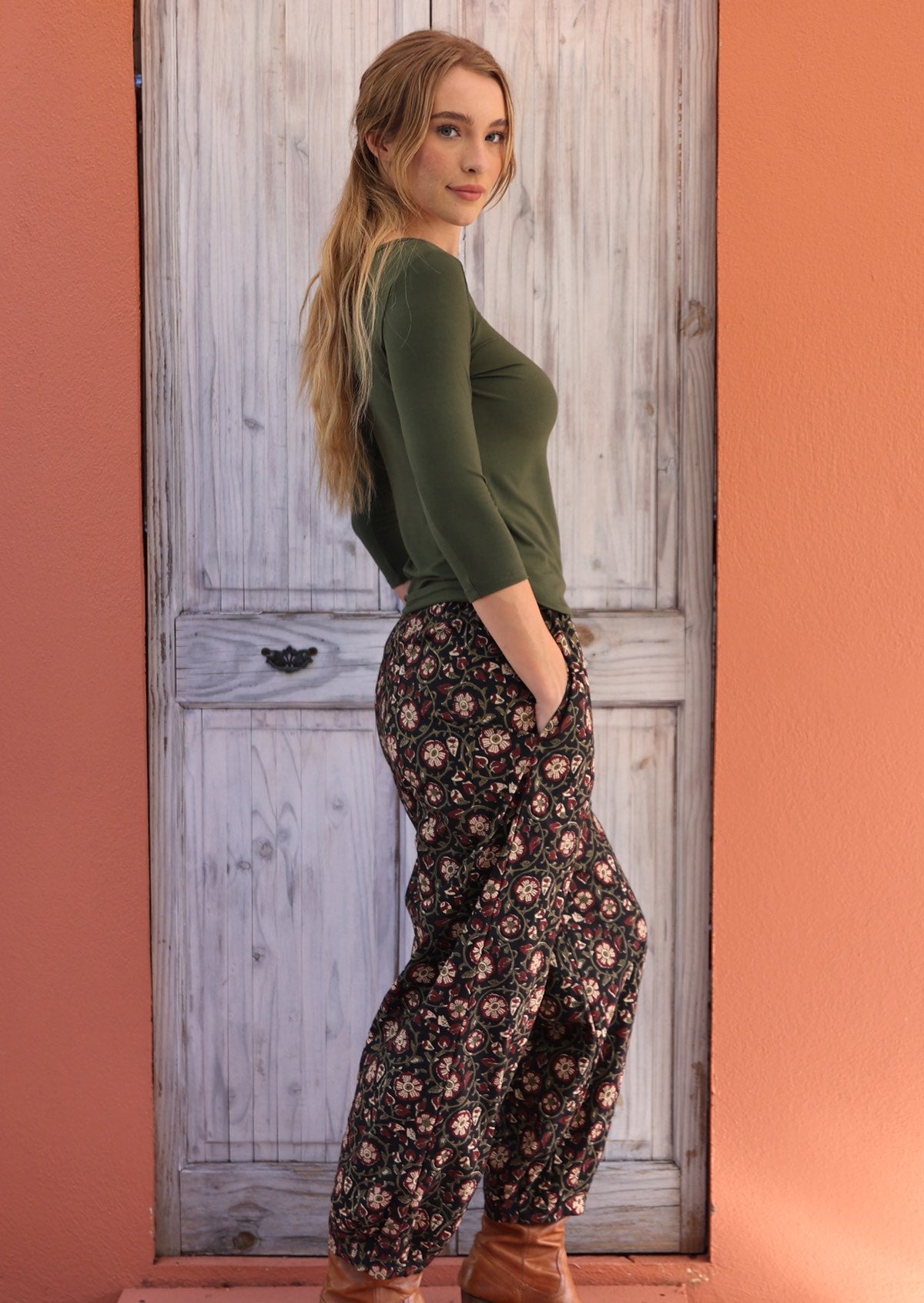 Woman standing sideways with hand in pocket wearing black based floral Indian 100% cotton pants