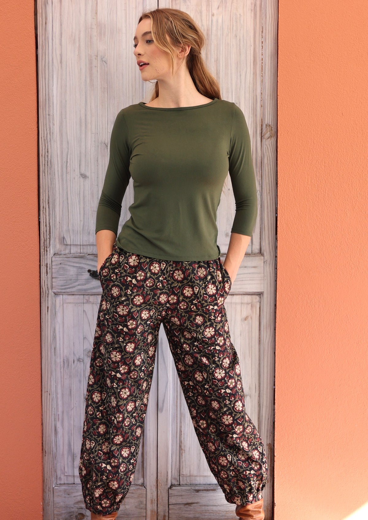 Woman standing with hands in pockets wearing black based floral Indian 100% cotton pants