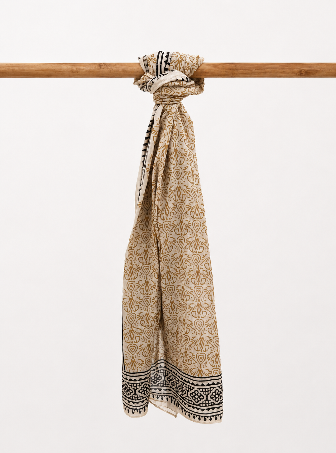 Beige patterned cotton scarf tied around a wooden stick on a white background