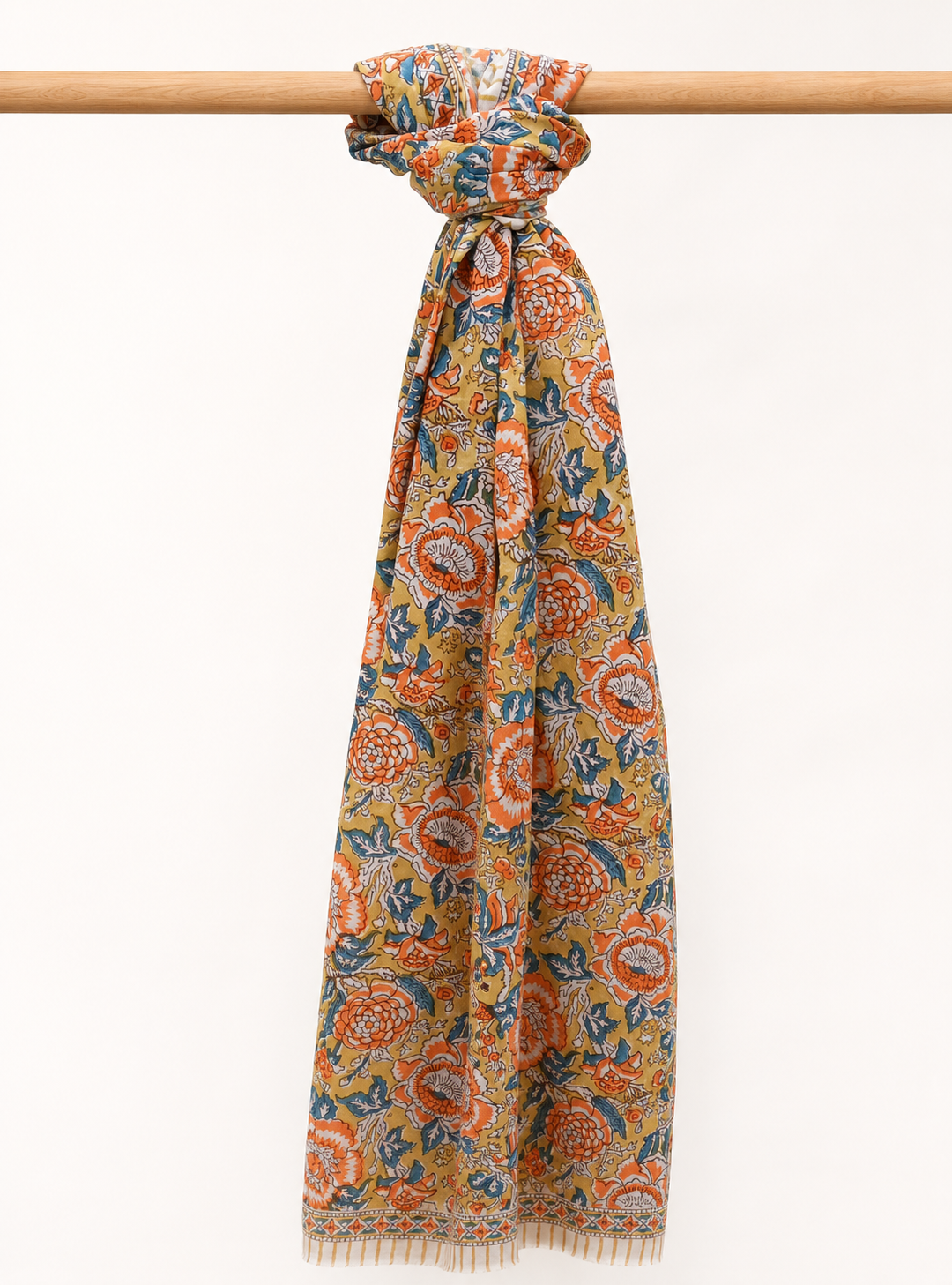 Colorful patterned cotton scarf on a wooden stick against a white background