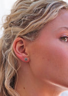 woman wearing sterling silver round Indian stud earrings with an ornate pattern.