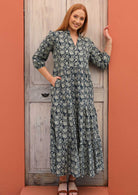 Model wears a three tiered maxi dress with a blue stamped floral pattern.
