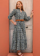 Model wears 100% cotton dress styled with a belt at the waist and sandals.
