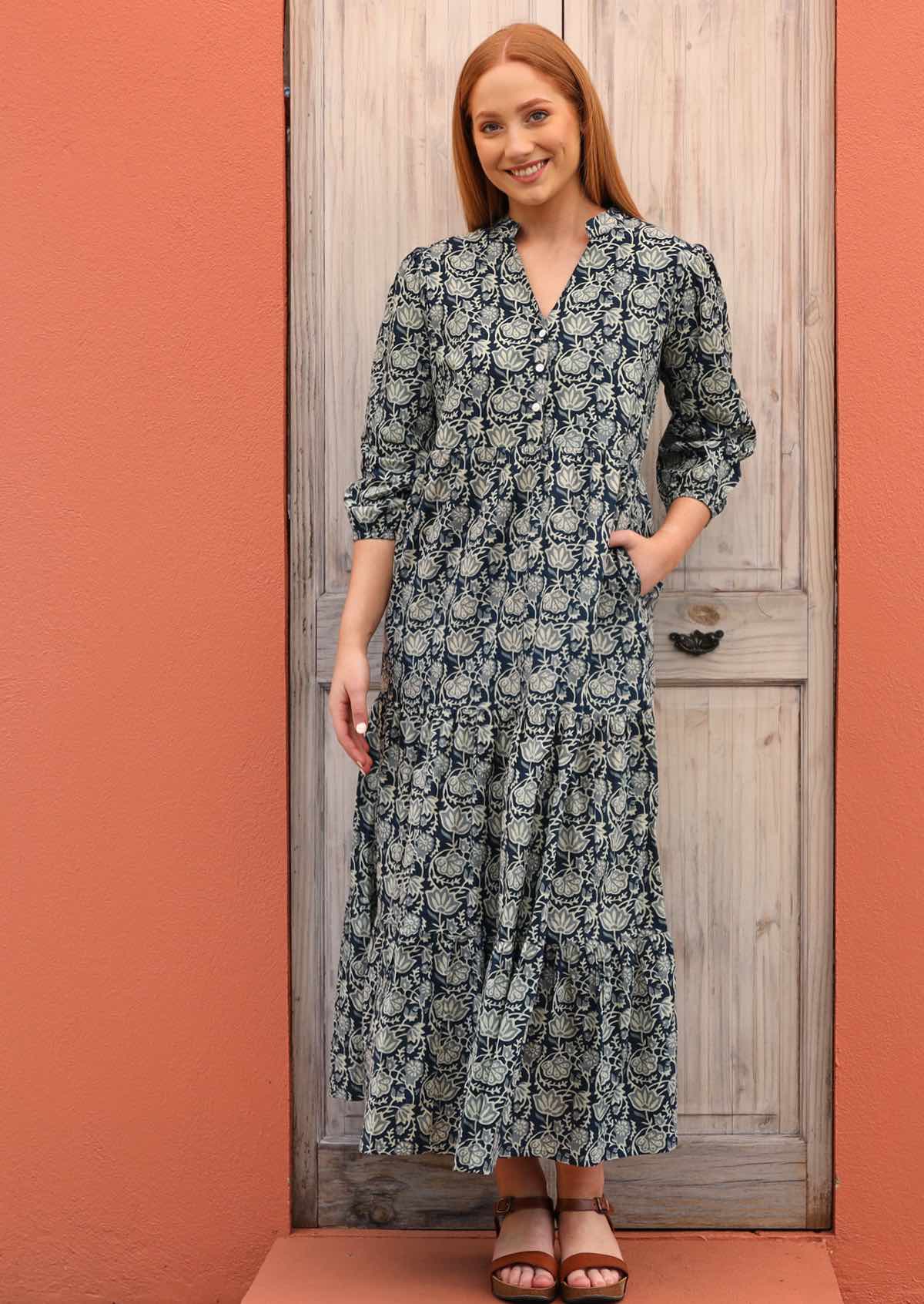 Woman has her hand in the pocket of her blue and white maxi dress.