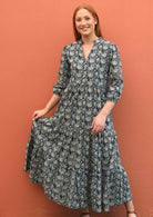 Model holds out the skirt of her stylish maxi dress.