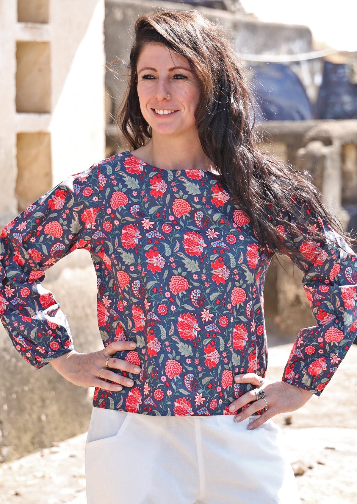 Model poses in cotton long sleeve top with boat neckline and bishop sleeves, in floral print