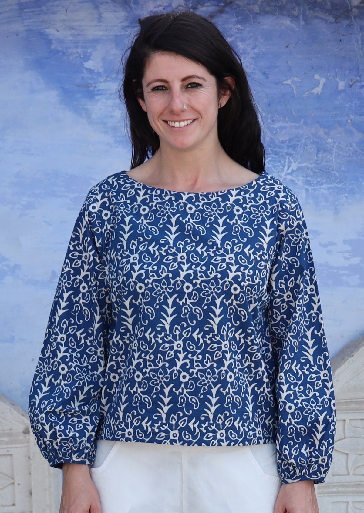 Woman wearing navy and off white boat neckline top with Bishop sleeves.