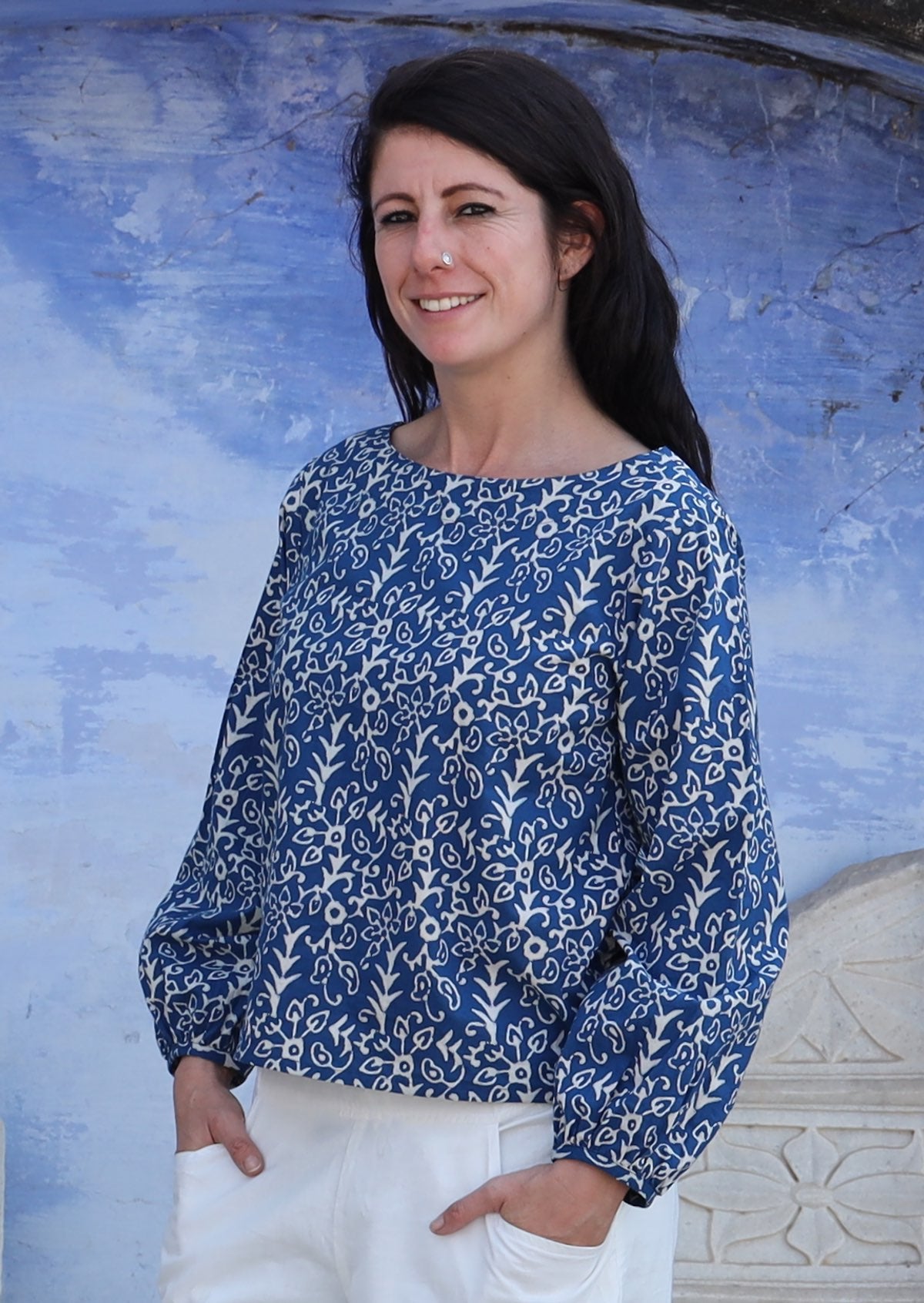 Woman with hands in pant pockets wearing navy and off white boat neckline top with Bishop sleeves.