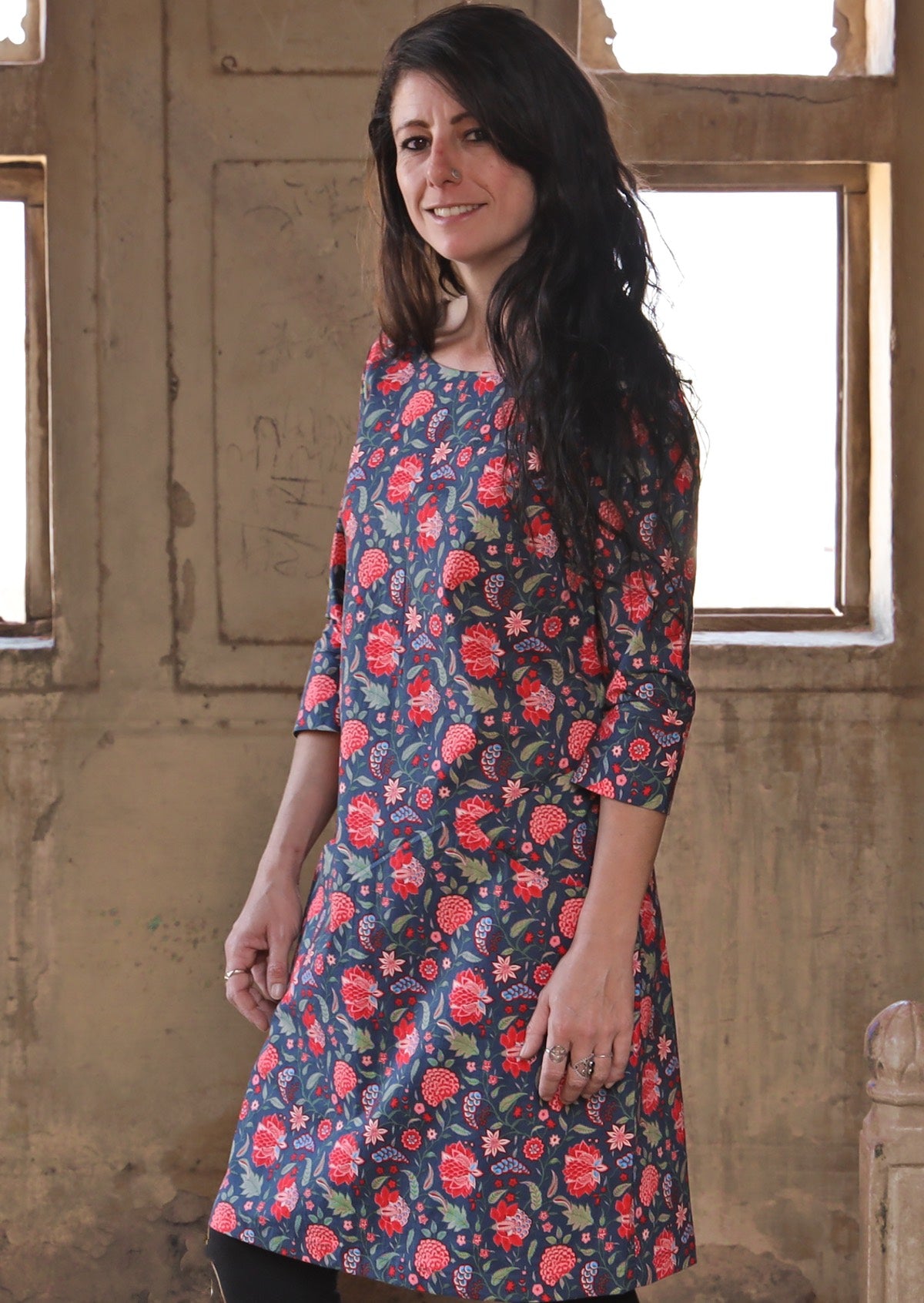 Woman wearing long sleeve 100 percent cotton dress with deep blue base and raspberry red floral print