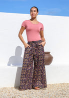 Model wears wide leg cotton floral printed pants with drawstring and hand in deep pockets.