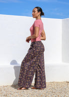 Model pairs dark purple based wide leg cotton pants with short sleeve stretch top in rose pink.