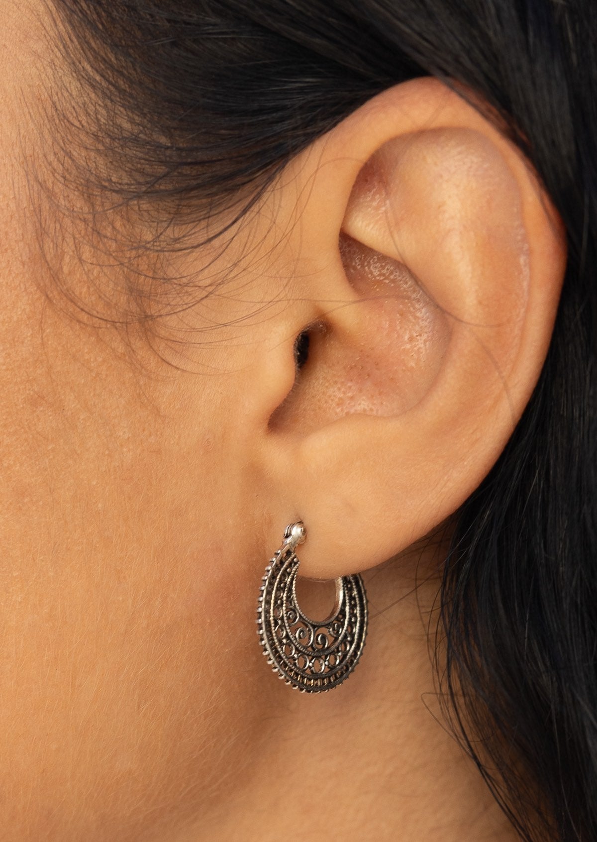 Close-up of a sterling silver mandala earring with intricate design and a clip closure
