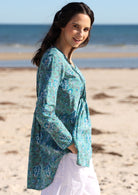 Side post of model wearing cotton long sleeve top with multiple small pleats at the front and back