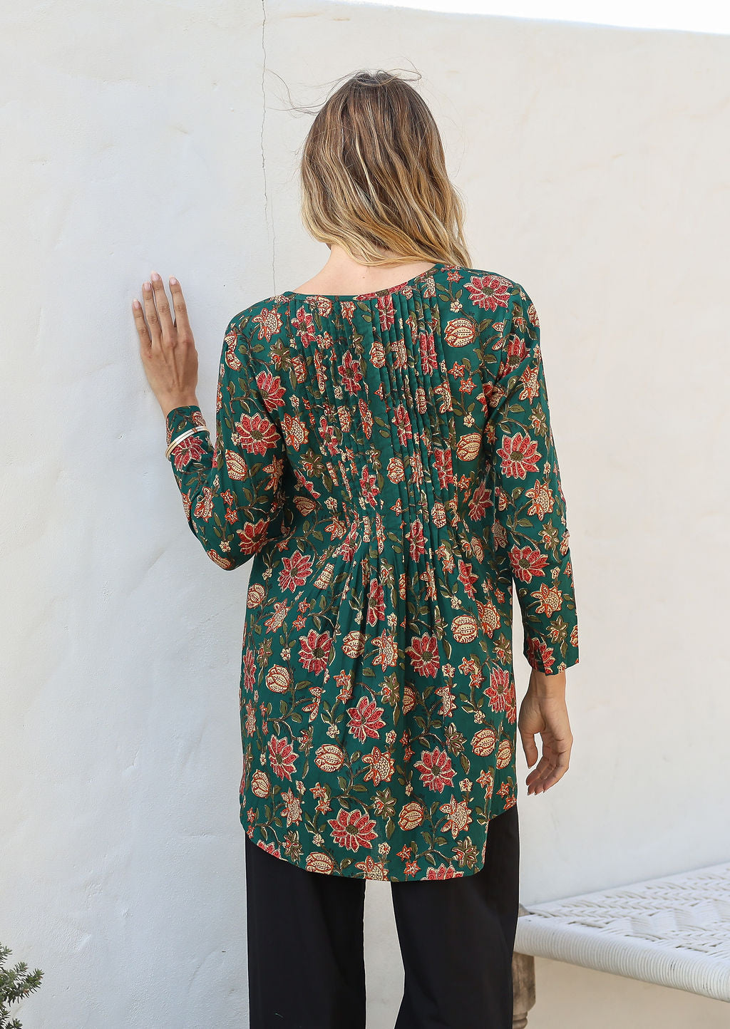 Back view of woman in cotton long sleeve shirt that is linger at the back, paired with black cotton pants