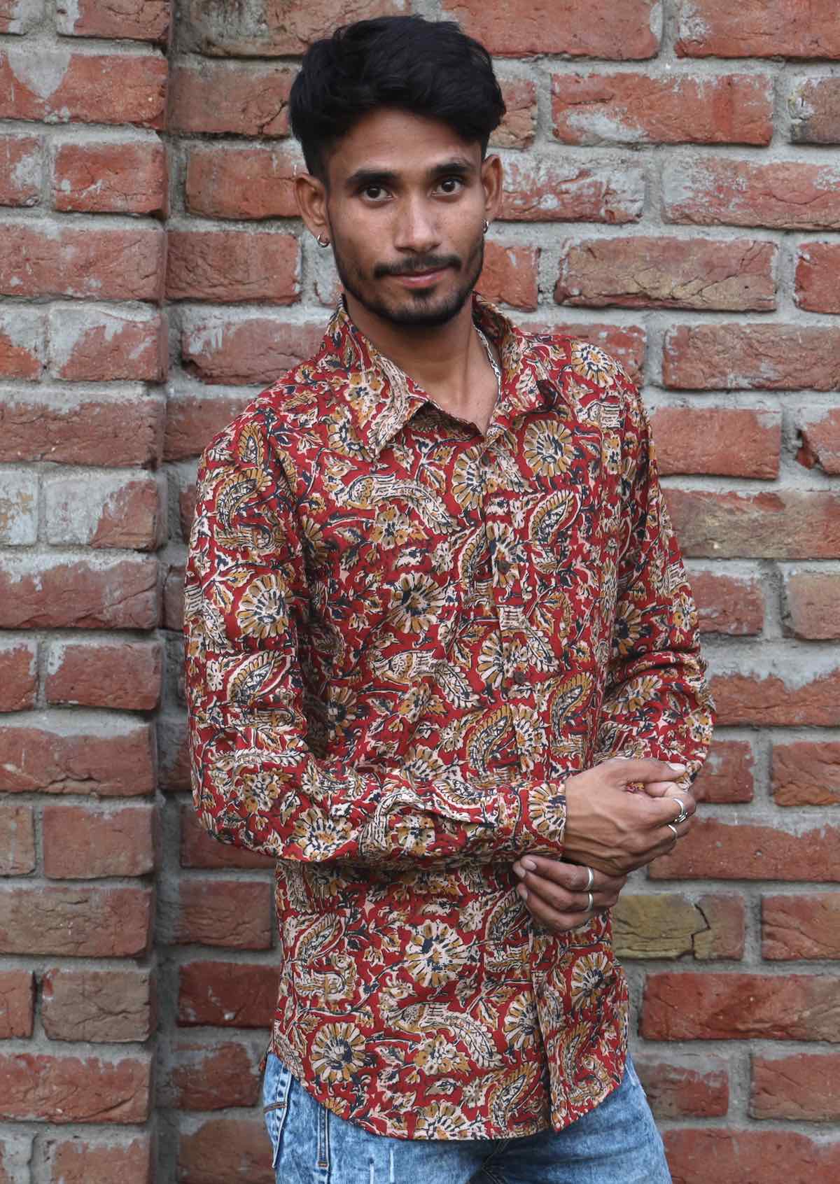 Man wears cotton long sleeve collared shirt with coconut buttons in Indian floral print on a rust base