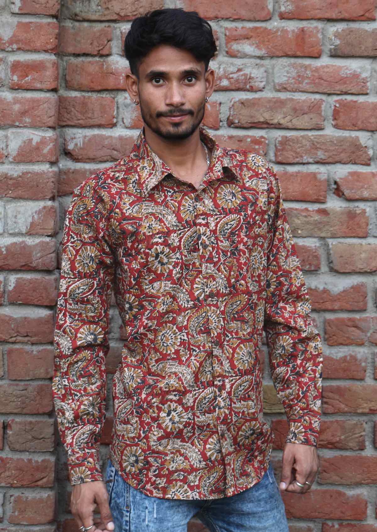 Man wears cotton long sleeve shirt with collar and coconut buttons in floral print with a rust coloured base