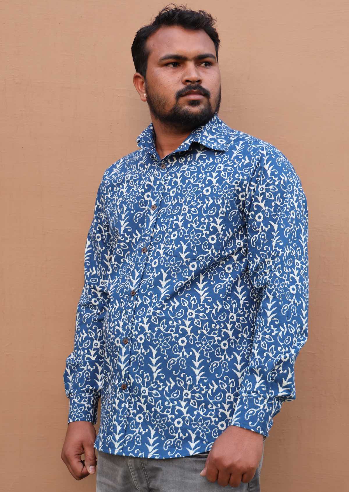 Man wears long sleeve cotton collared shirt with coconut buttons through the centre front and the cuffs