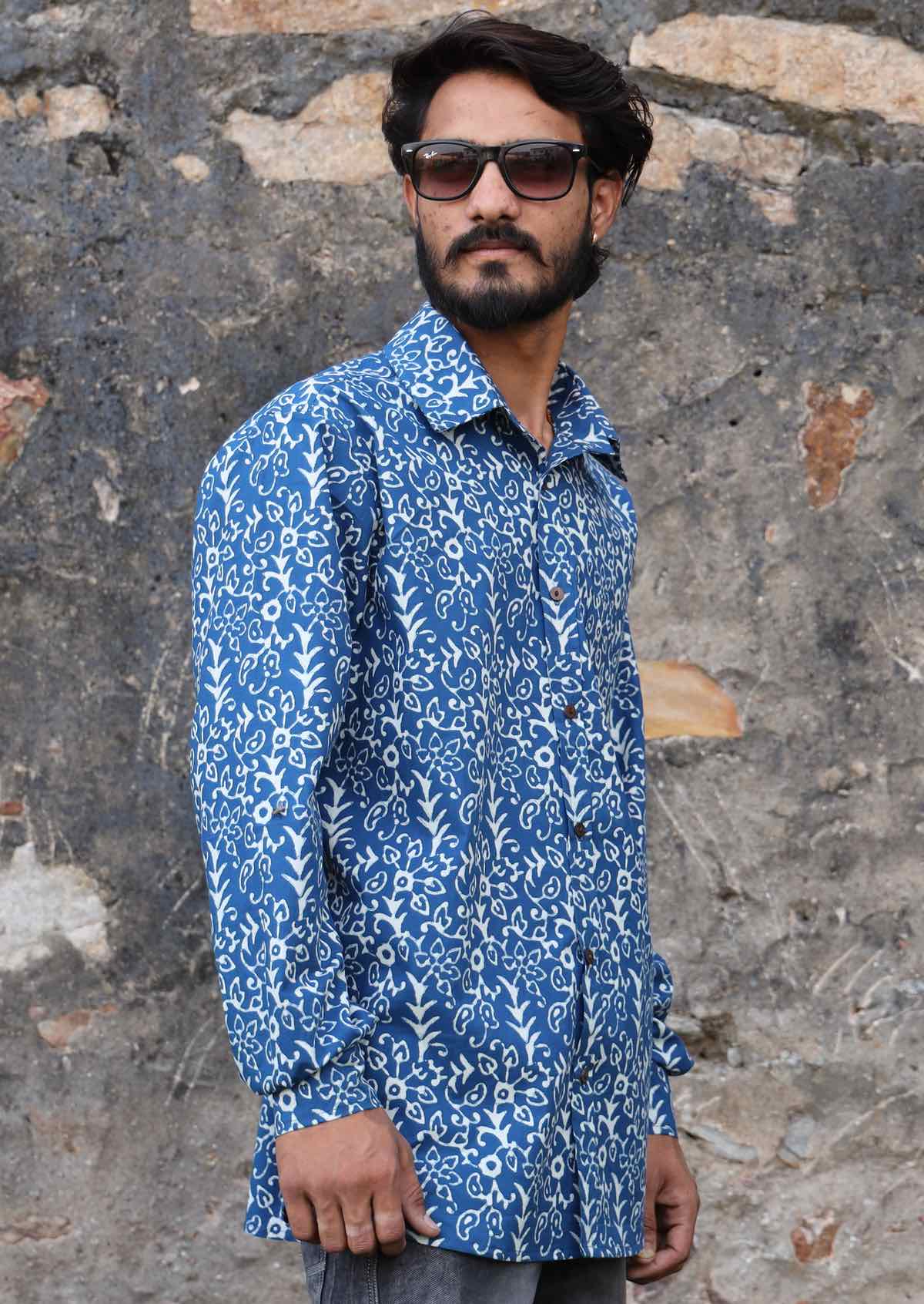 Man wears cotton blue based white floral print shirt, with a collar and cuffed sleeves