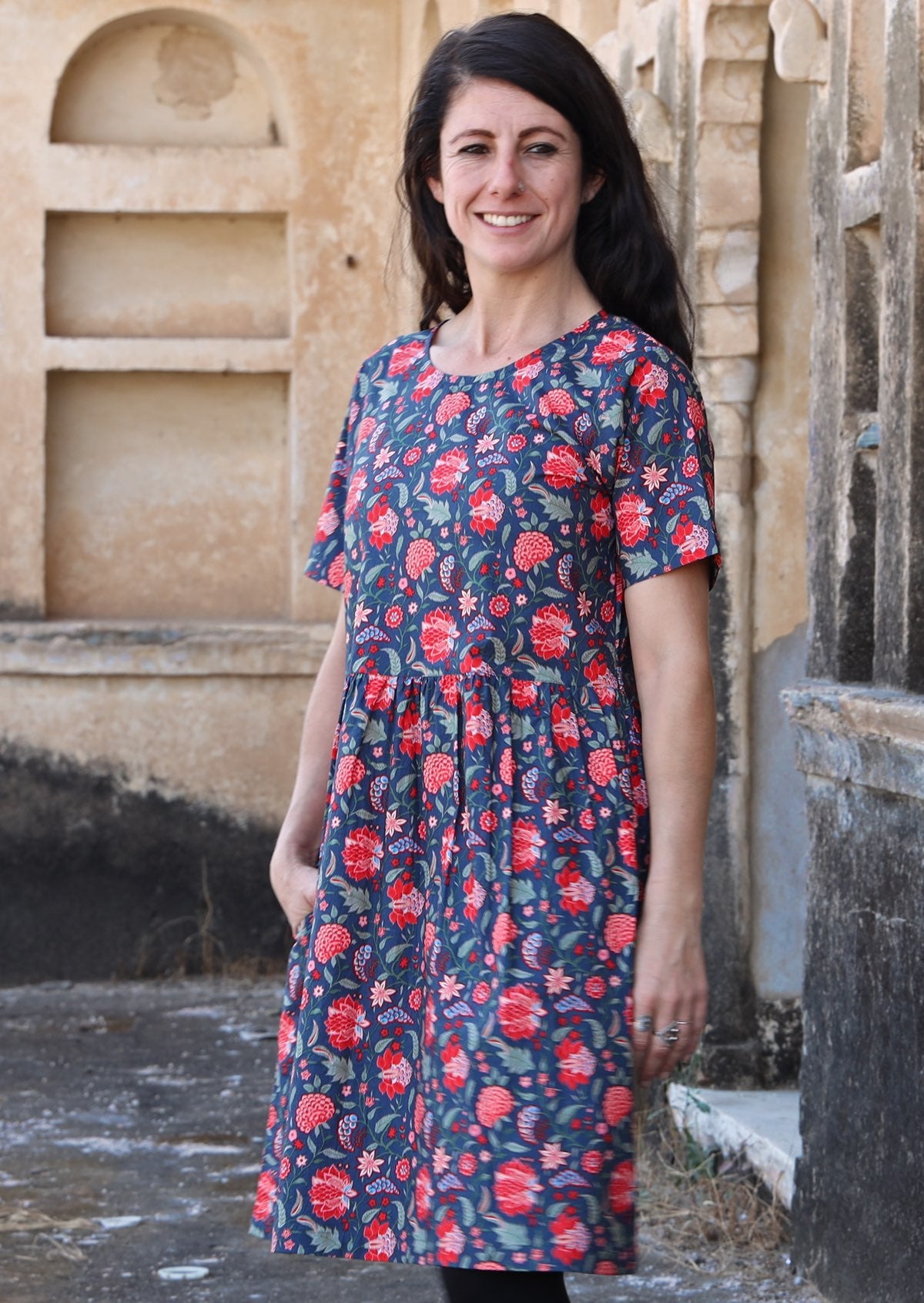 Woman wearing 100 percent cotton blue base retro dress with leaf and floral print with hand in pocket