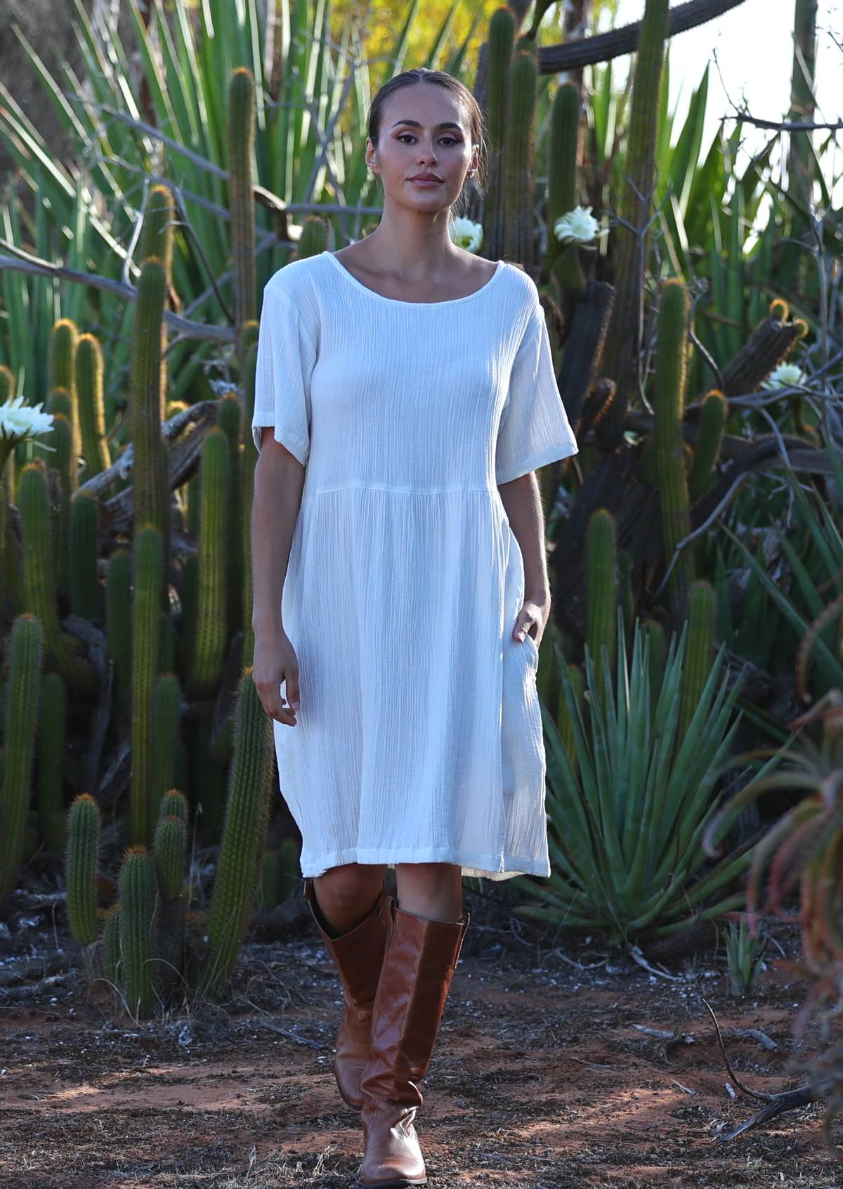 Woman with dark hair wearing natural white double cotton short sleeve sundress in front of cacti