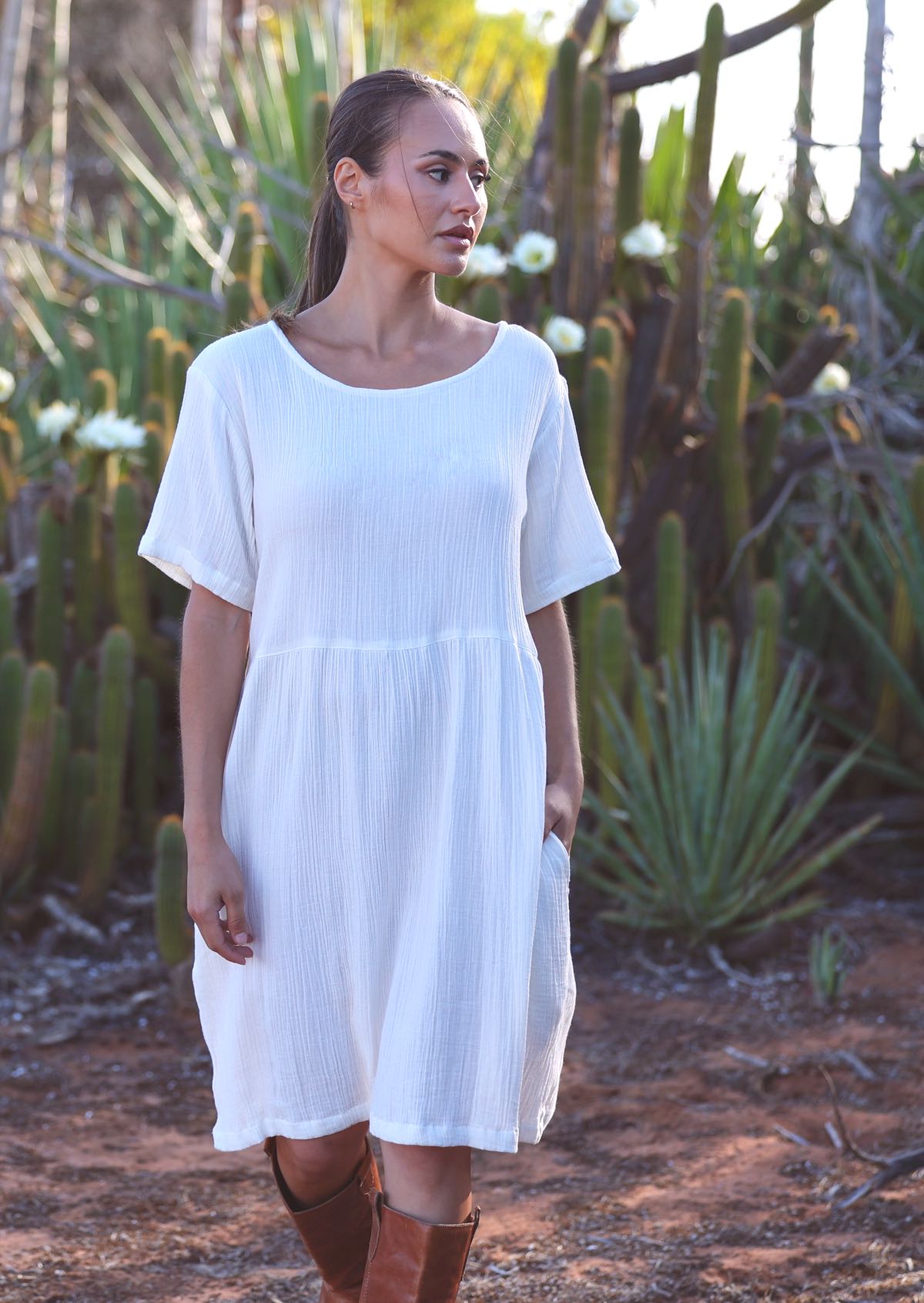 Woman with dark hair wearing white pure 
cotton short sleeve sundress in front of cacti